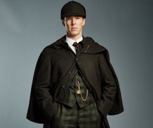 Benedict Cumberbatch wearing a suit and tie standing in front of a coat