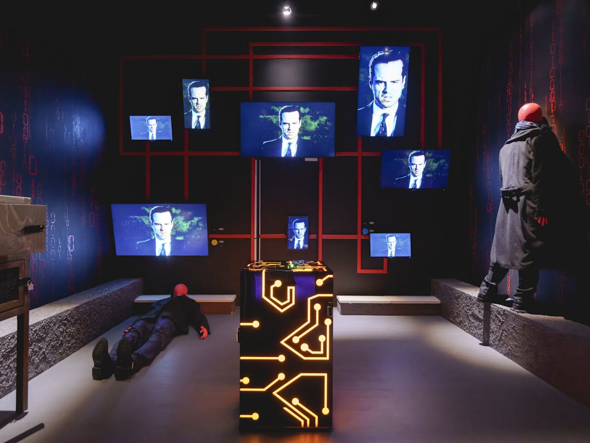 A room with screens featuring Andrew Scott in the new escape room, The Mind of Moriarty