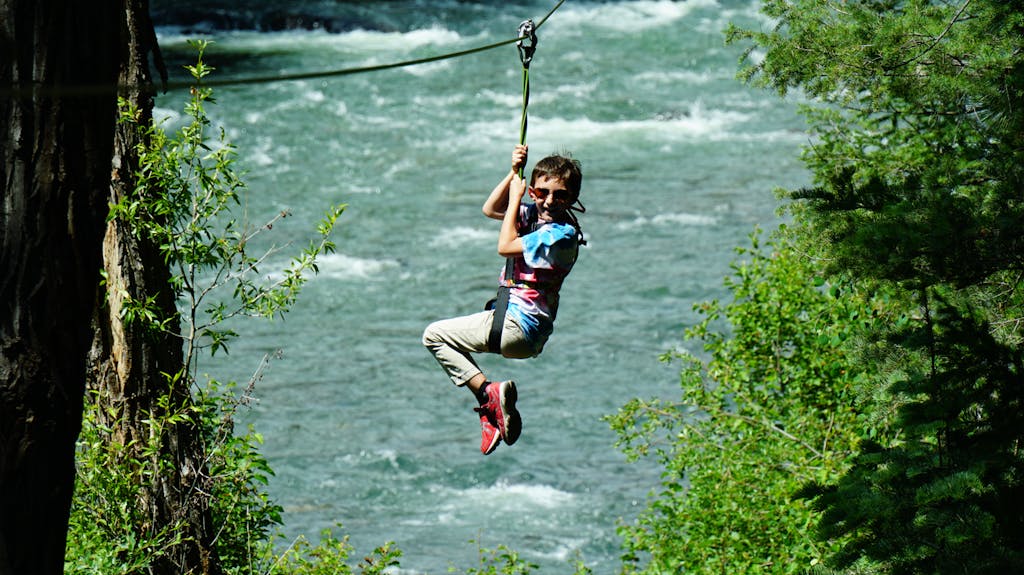a boy ziplining over the water