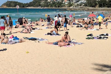 a group of people sitting at a crowded beach on a sunny day