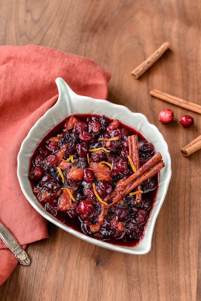 a bowl of cranberries sitting on top of a wooden table