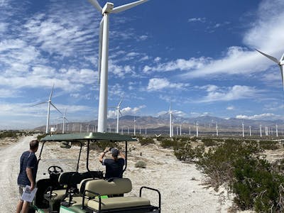 a group of people observing modern wind turbines