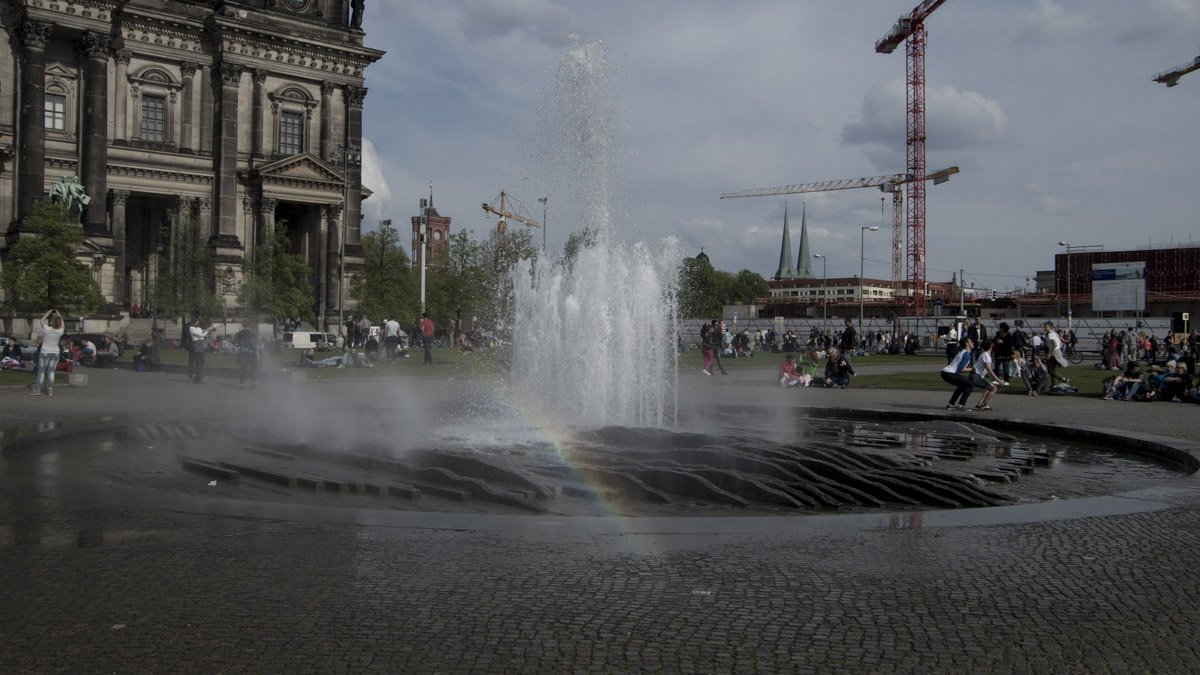 Regenbogen am Lustgarten, mit jeweils einer Ecke vom halbfertigen Humboldtforum und dem Berliner Dom im Hintergrund.
