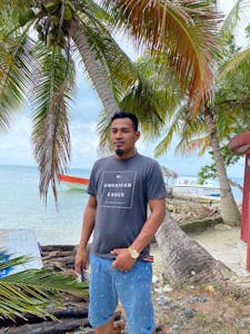 a man standing next to a palm tree next to a body of water