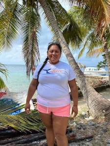 a person standing next to a palm tree next to a body of water