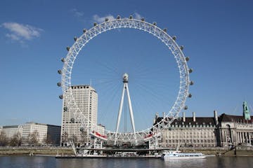 a large ship in a body of water with London Eye in the background