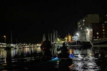a small boat in a body of water with a city in the dark
