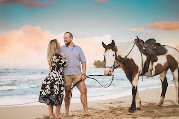 a man and a woman photoshoot with horse on a beach