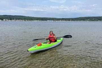 a girl wearing a lifejacket in georgian bay paddle in a green single kayak