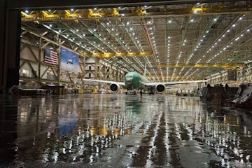 reflective photo of a jumbo jet in a hangar at boeing factory