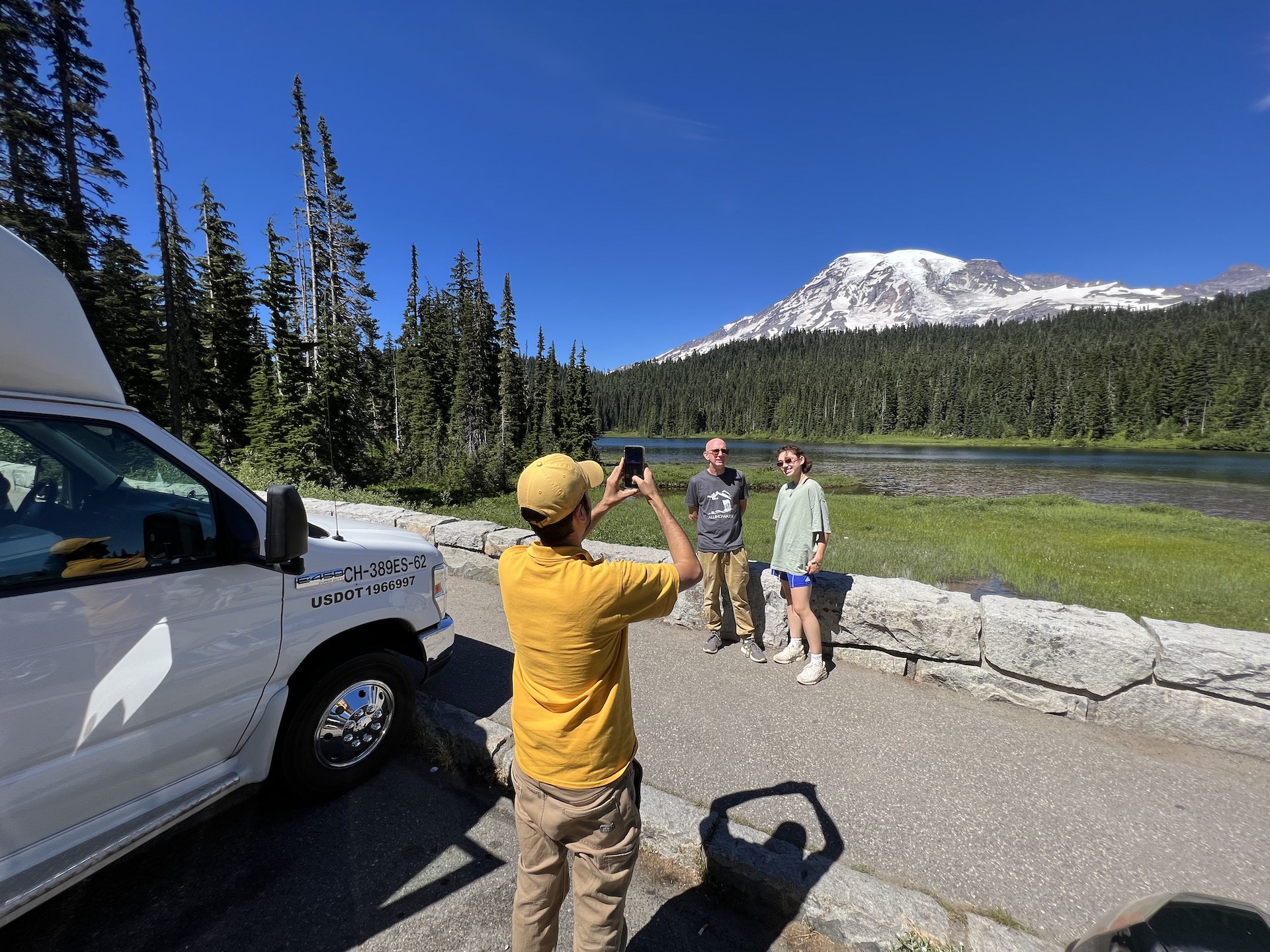 person taking a photo of people in front of trees and mountain