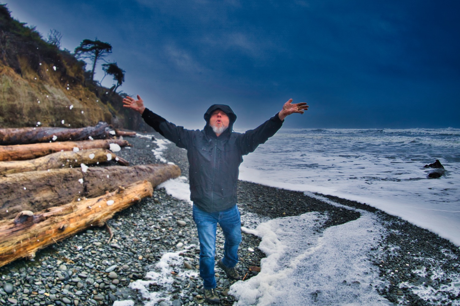 a man that is standing on the Kalaloch Beach next to the water with his hands in the air on an Olympic National Park Tour