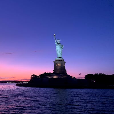 purple and pink sky behind the Statue of Liberty during a sunset cruise in NYC