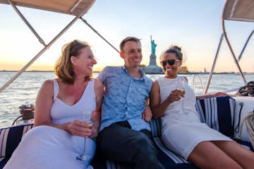 3 friends sailing by the Statue of Liberty on a private boat tour in NYC