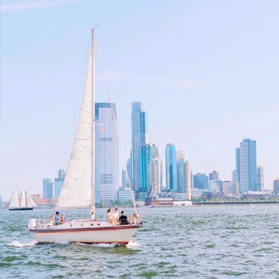 sailboat in the New York Harbor with the city skyline in the background during a NYC boat charter