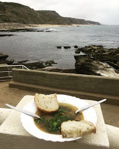 um prato de sopa de lapas frente a uma praia 