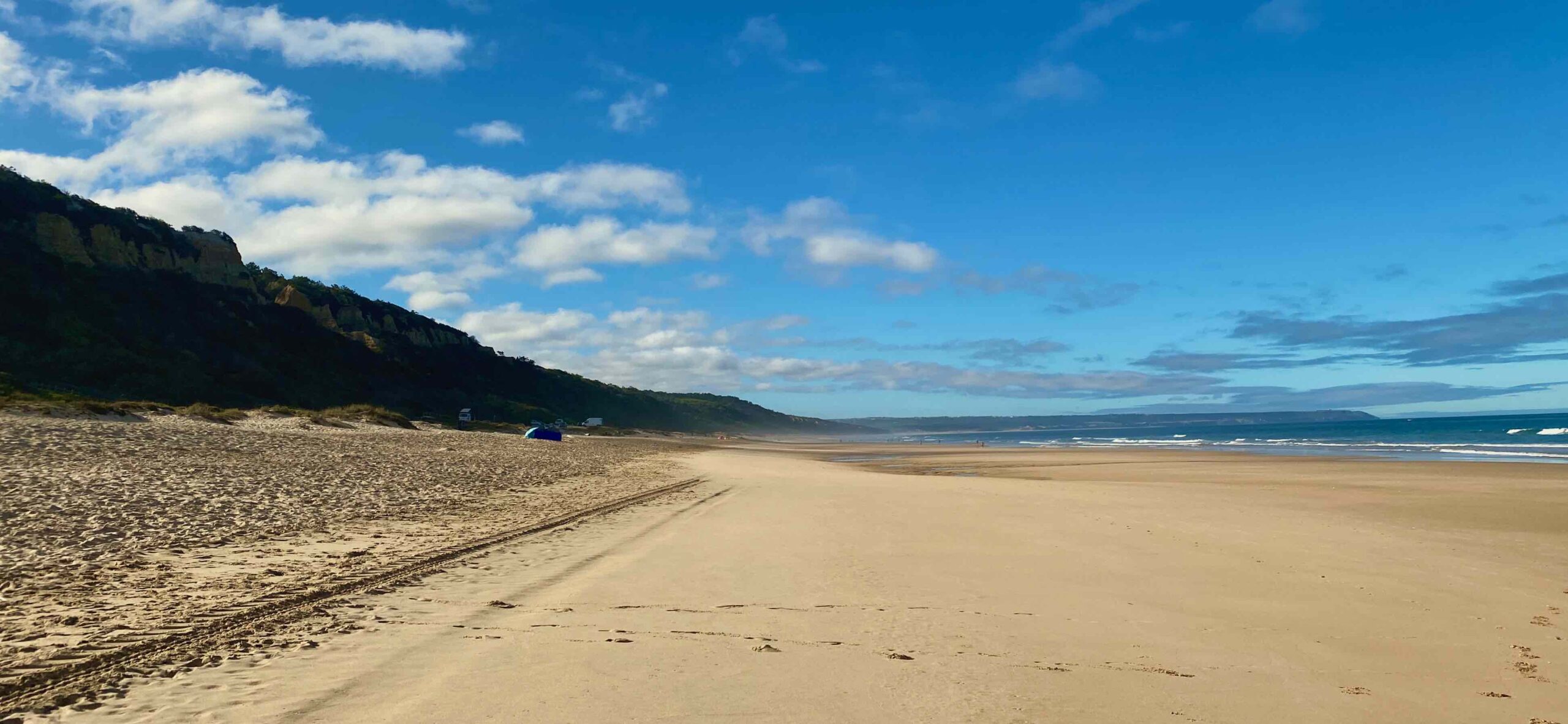 a sandy beach with Polihale State Park in the background