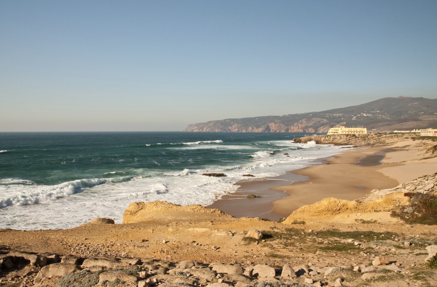 a sandy beach next to the ocean