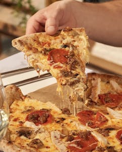 a close up of a person holding a slice of pizza