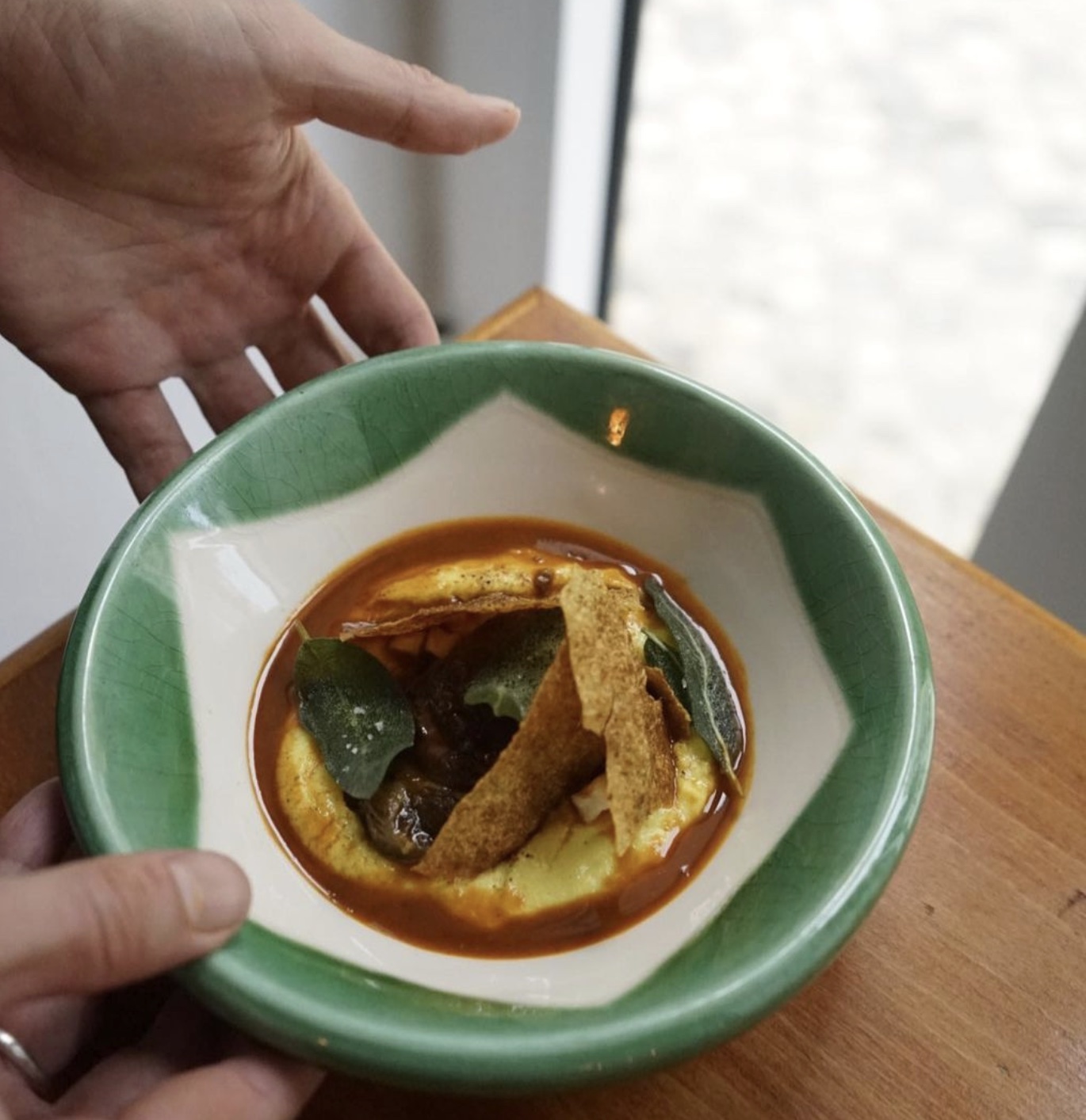 a hand holding a green bowl on a table