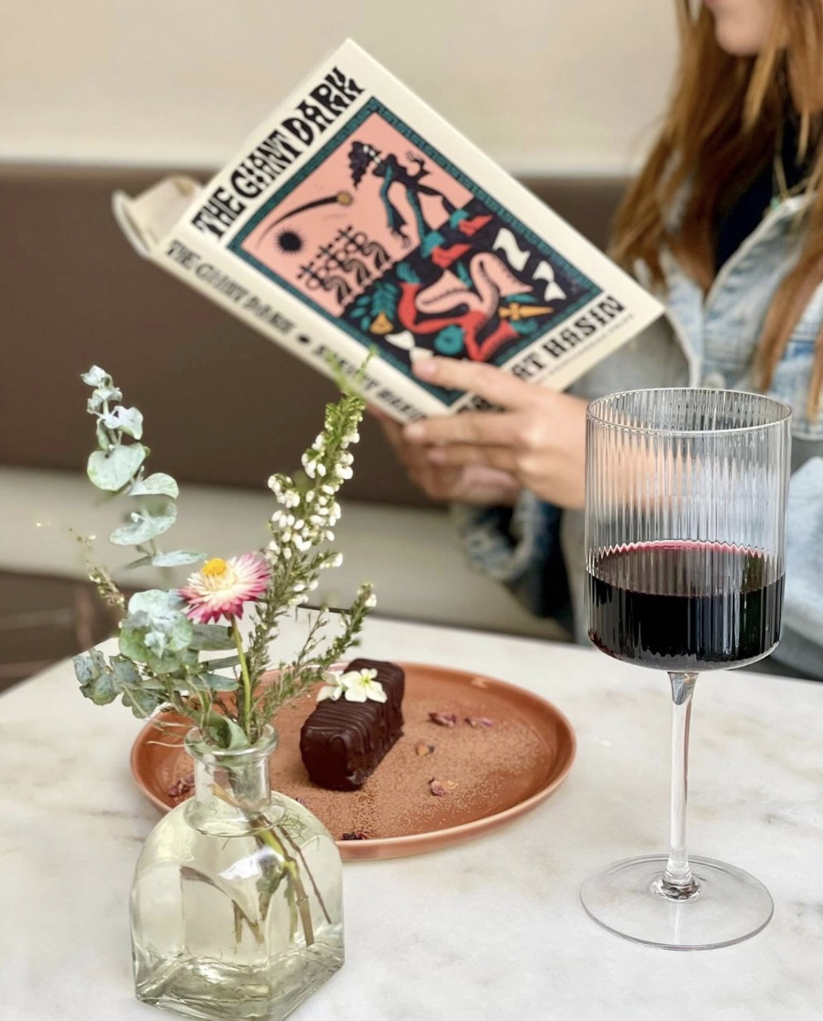 a woman sitting at a table with wine glasses