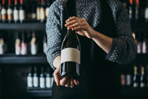 a person presenting a wine bottle in a wine bar