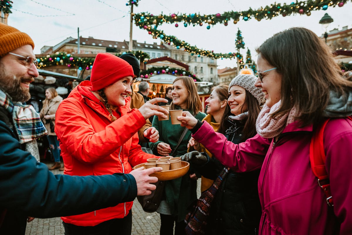a group of tourists and a tour guide raising a glass of hot drink at the Christmas Markets in Prague