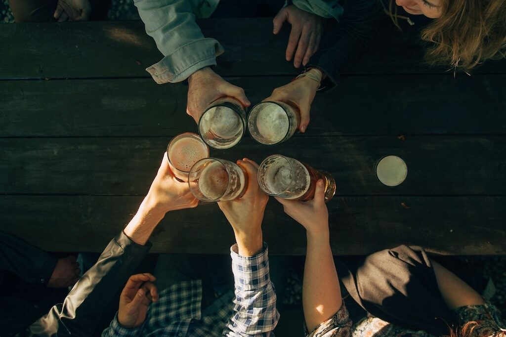 a group of people toasting with their beer glasses in an open-air bar in Prague