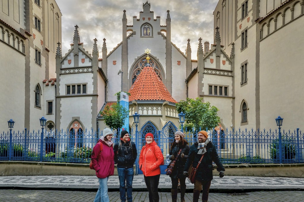 a group of tourists and a tour guide standing in front of the beautiful Maisel synagogue in the Jewish Quarter of Prague