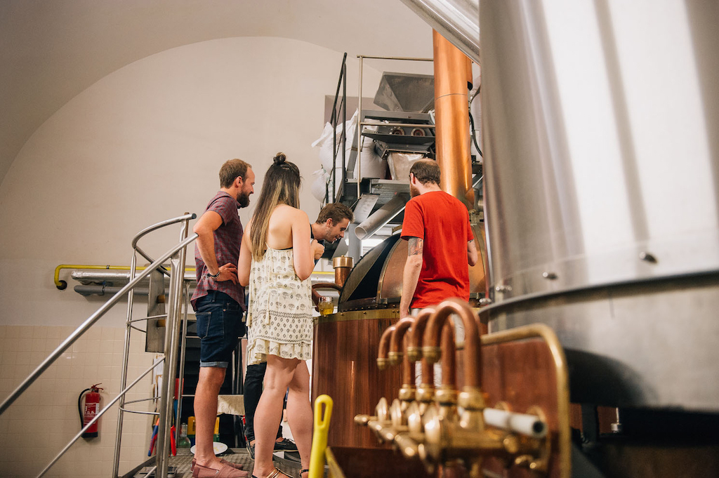 a group of tourists exploring the Original Pilsner Urquell Brewery on a guided tour