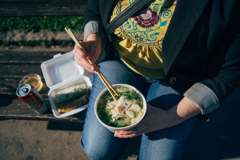 a person eating a pho soup from a plastic cup during the Asia fest in Prague