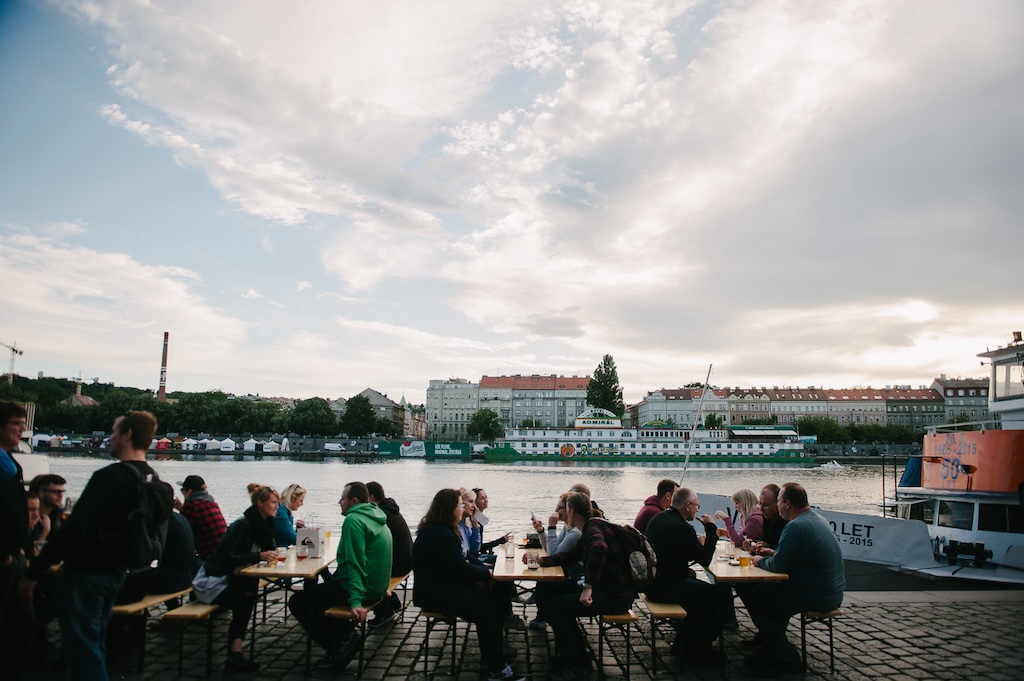 people sitting at an open-air bar on the banks of the Vltava River in Prague