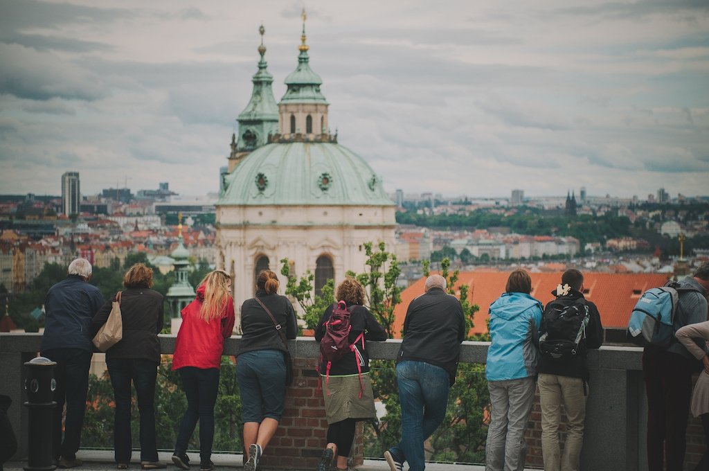 a group of tourists and a tour guide overlooking the city of Prague