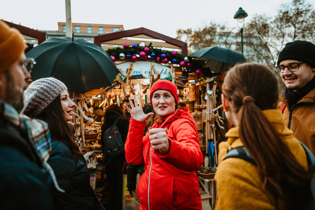 a tour guide explaining Czech Christmas traditions to a group of tourists at the Christmas Markets in Prague