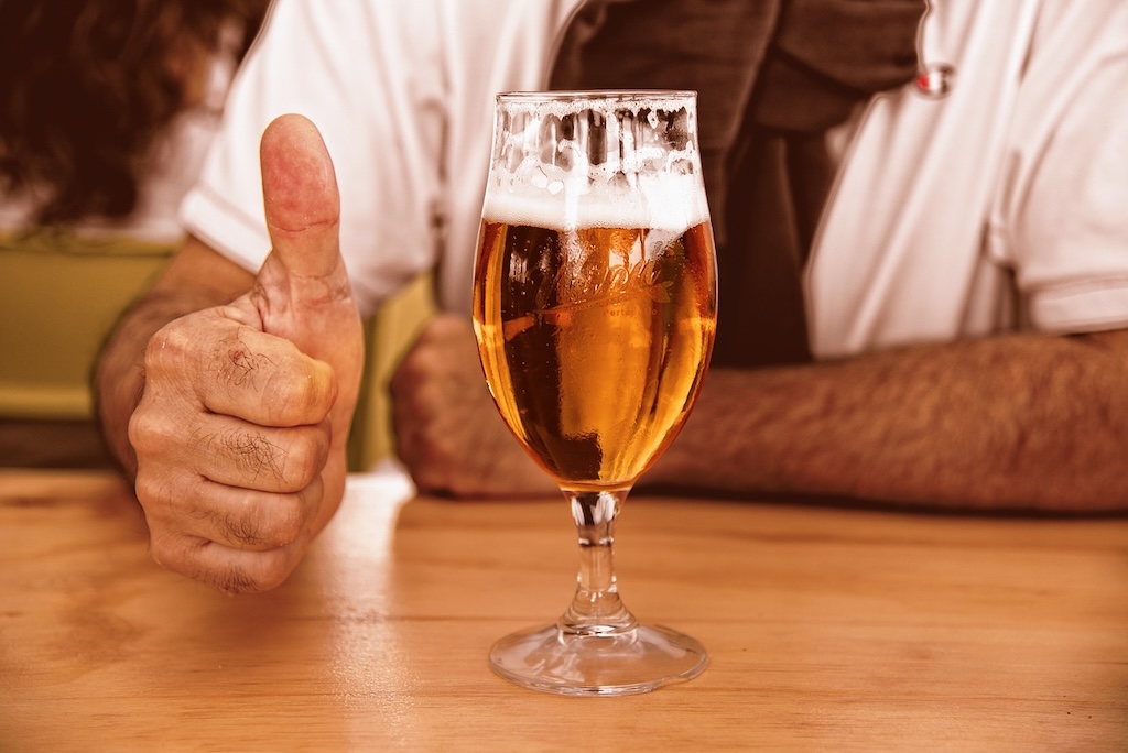 a glass of delicious Czech beer next to an old hand with thumbs-up