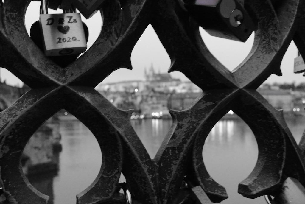 a railing on a bridge in Prague with the view of Prague Castle in the background