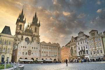 the Old Town Square of Prague at sunrise, with the Tyn Church dominating the scene