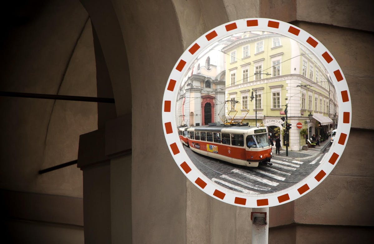 a safety mirror showing a tram passing by in the Lesser Town of Prague