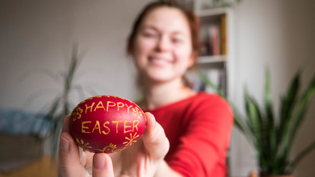a girl holding a decorated egg saying happy easter up