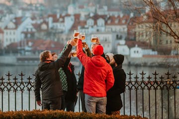 a group of people raising a glass of beer by the Charles Bridge in Prague