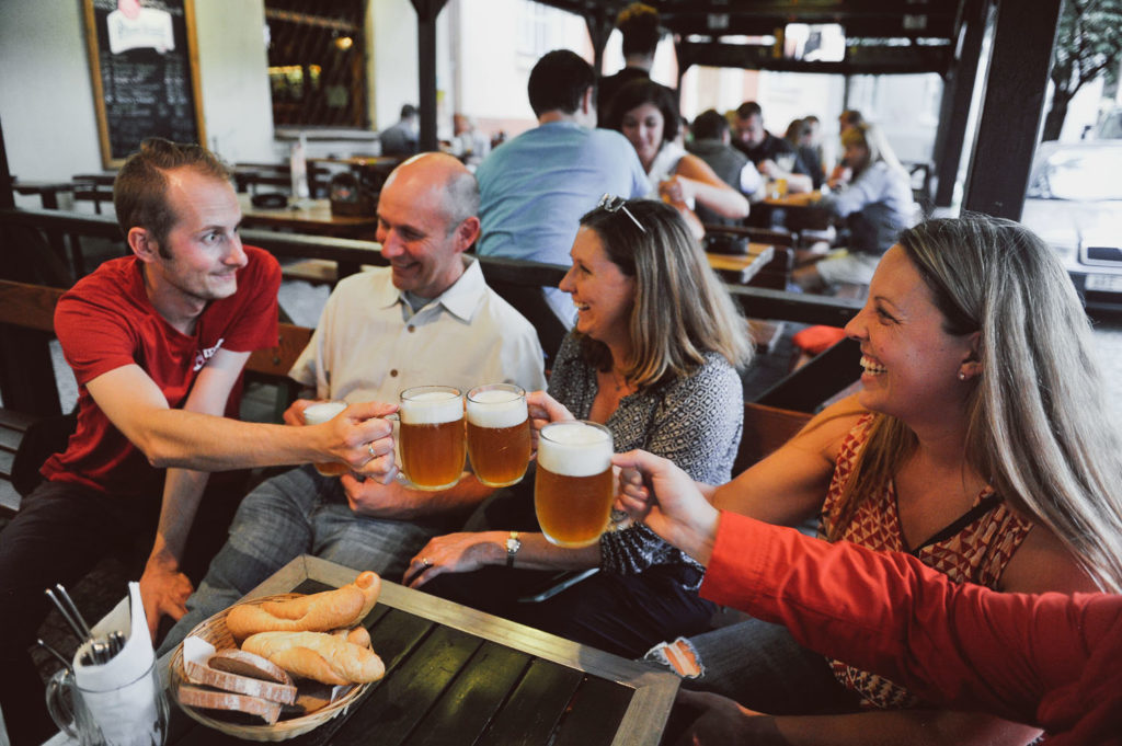 a group of tourists raising their glasses of beer together with a tour guide on a Beer Tour in Prague