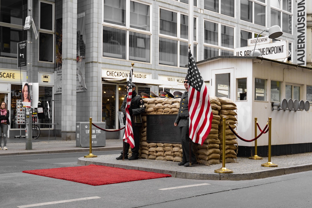 a person walking down a street next to Checkpoint Charlie