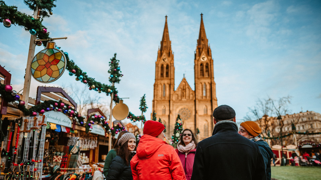a group of tourists with a tour guide on the Christmas Markets in Namesti Miru during a Prague Christmas Markets Tour