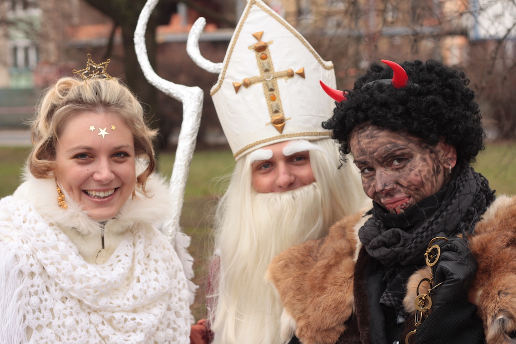 a group of people dressed as an Angel, Devil, and St. Nicolas in the middle