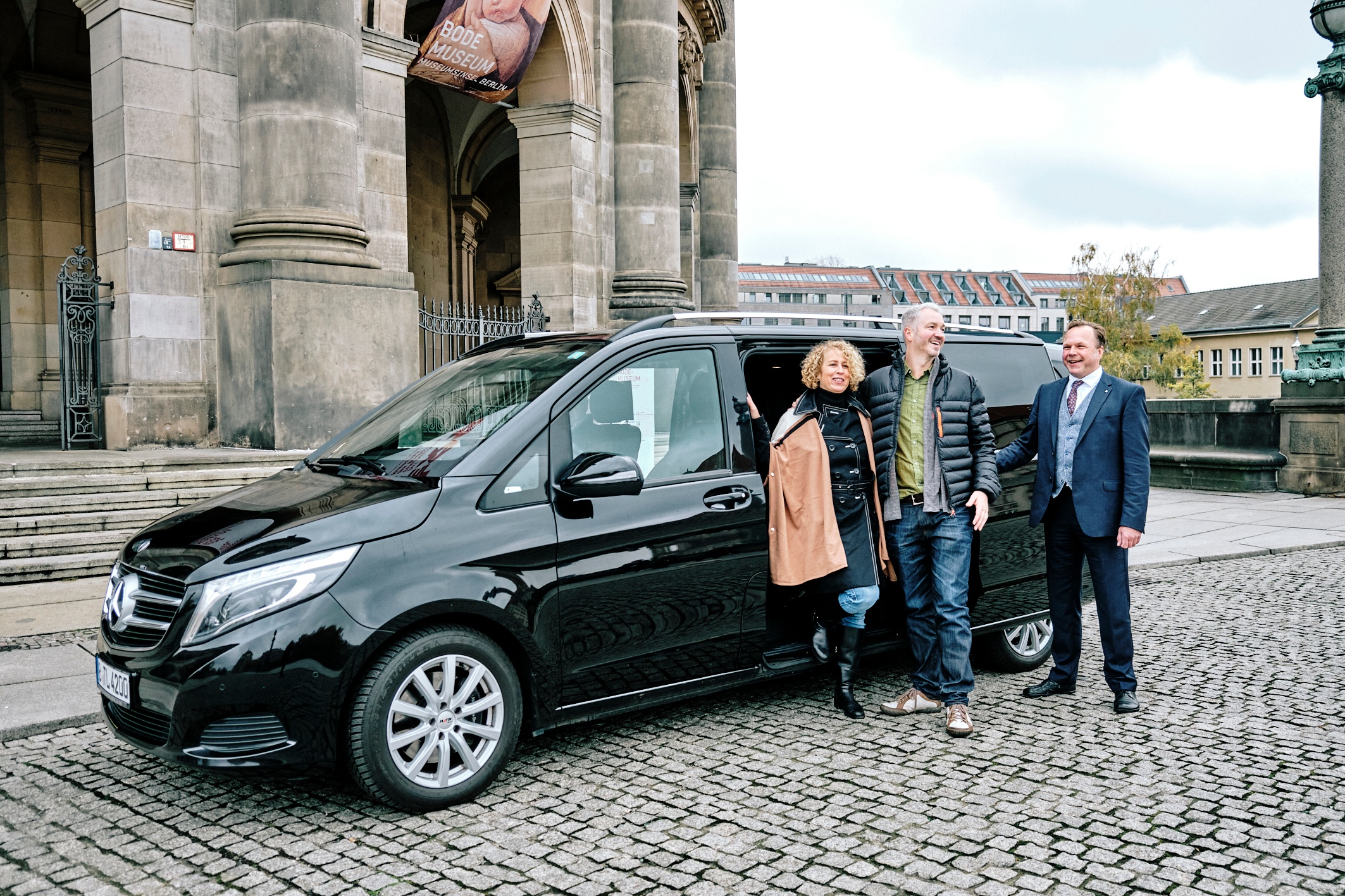 a couple of tourists standing beside their friendly looking driver and a comfortable looking van