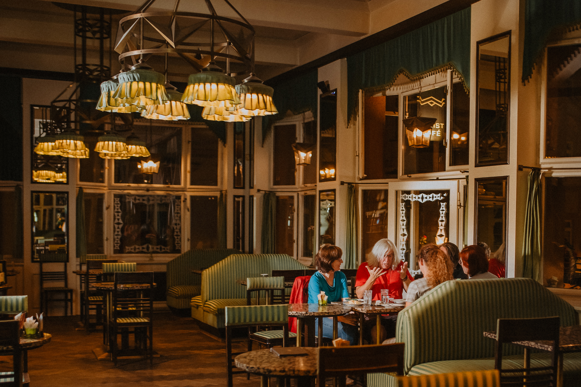 a group of tourists and a tour guide enjoying coffee and a dessert at a cosy coffee shop in Prague