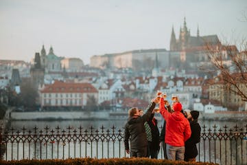 a group of people enjoying a glass of beer with a view of Prague Castle on a winter day in Prague