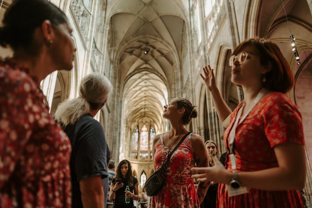a group of tourists together with a tour guide inside the St. Vitus Cathedral on a Prague Castle Tour
