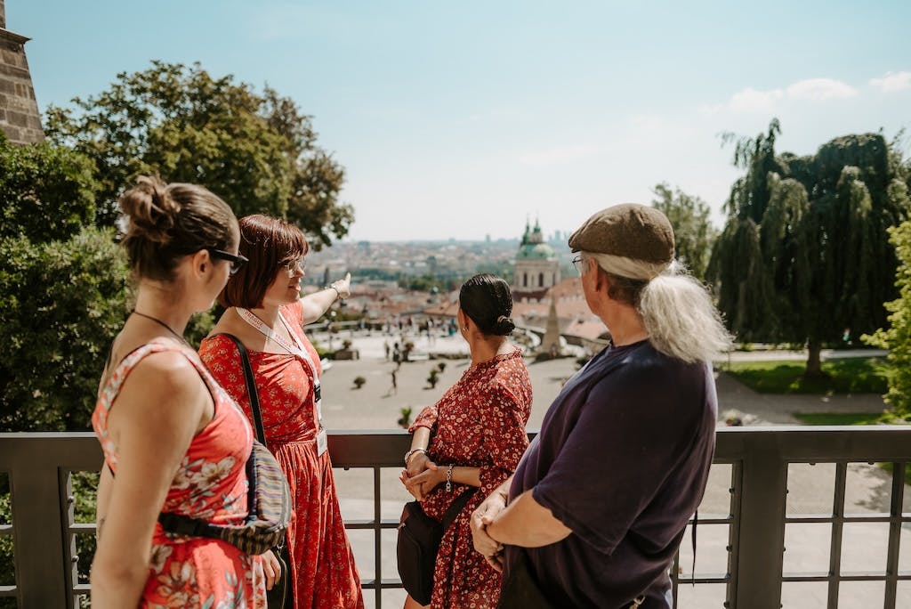 a tour guide pointing to St. Nicolas Church in front of a group of tourists on a Prague Castle tour