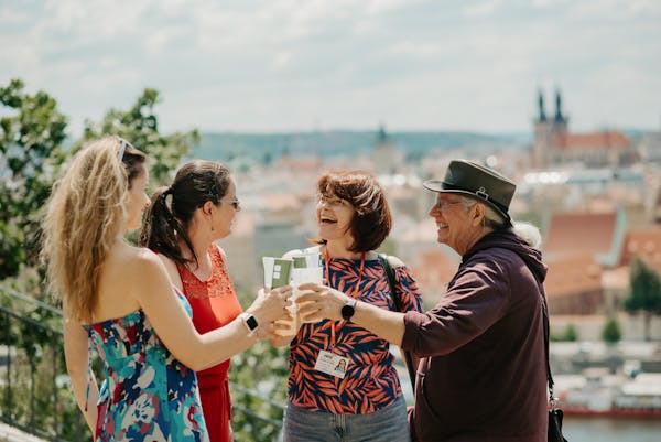 a private group of tourists in Prague enjoying a glass of beer with a stunning view of Prague in the background